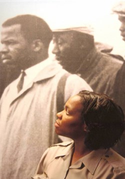 A National Park Ranger looks up at a museum exhibit featuring a historic image of men marching for civil rights. A National Park Ranger looks up at a museum exhibit featuring a historic image of men marching for civil rights.