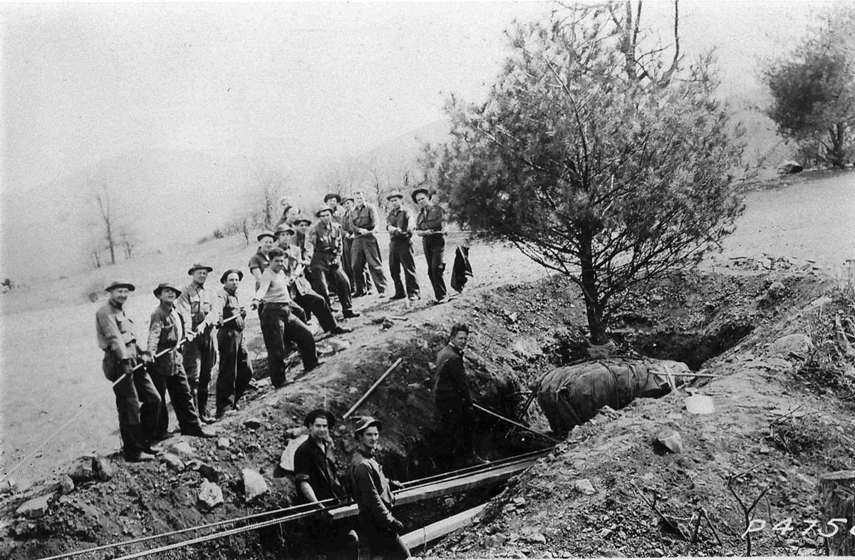 Black and white historical photograph of young men planting a tree.