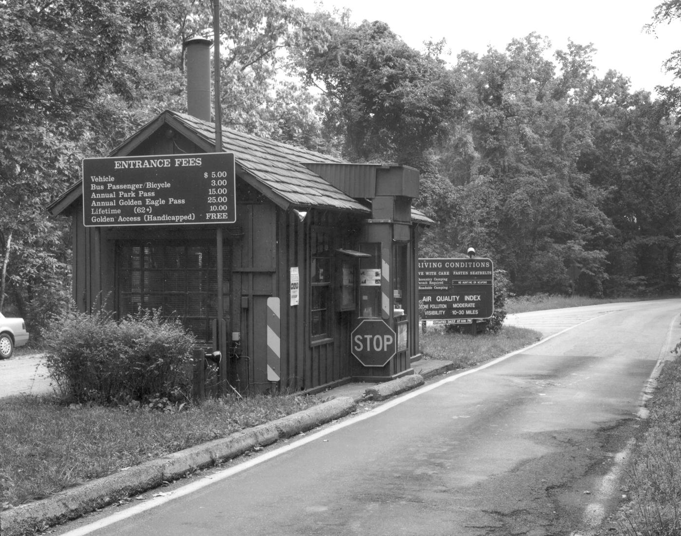 Black and white photo of Rockfish Gap Entrance Station, a small building with signs, along skyline drive