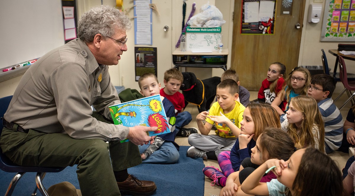 A ranger in a classroom reading to students A ranger in a classroom reading to students