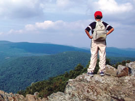 A young boy stands on the rocky top of Hawksbill mountain and takes in a great view. A young boy stands on the rocky top of Hawksbill mountain and takes in a great view.