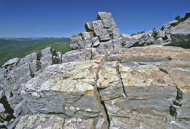 Rocks covered in lichen overlooking a valley.