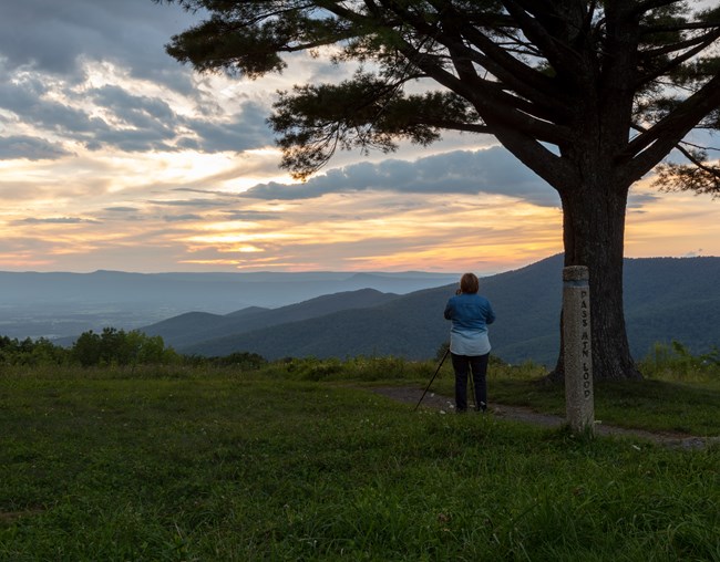 A photographer with a tripod captures a sunset over the Shenandoah Valley from Pass Mountain Overlook.