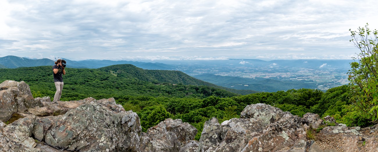 Hiker with a camera on the rocky stony man summit