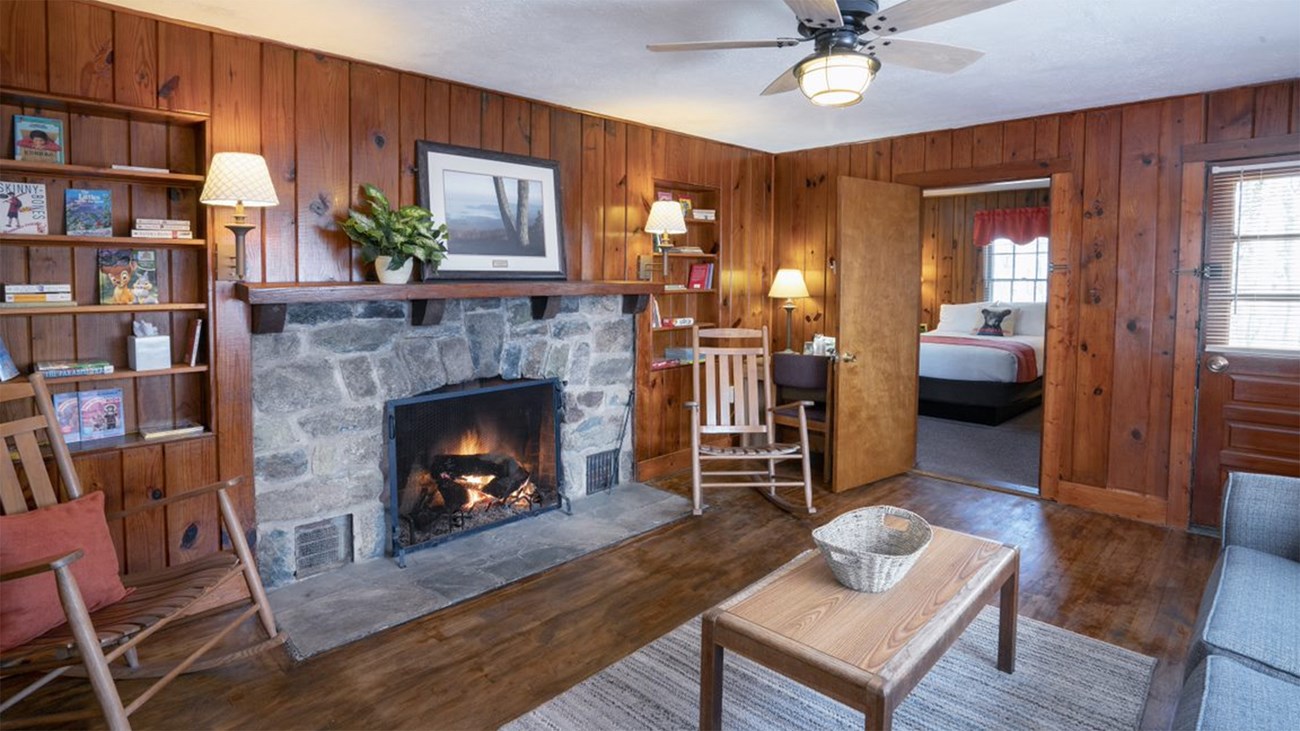 The interior of a lodge with wood walls and a stone fire place.