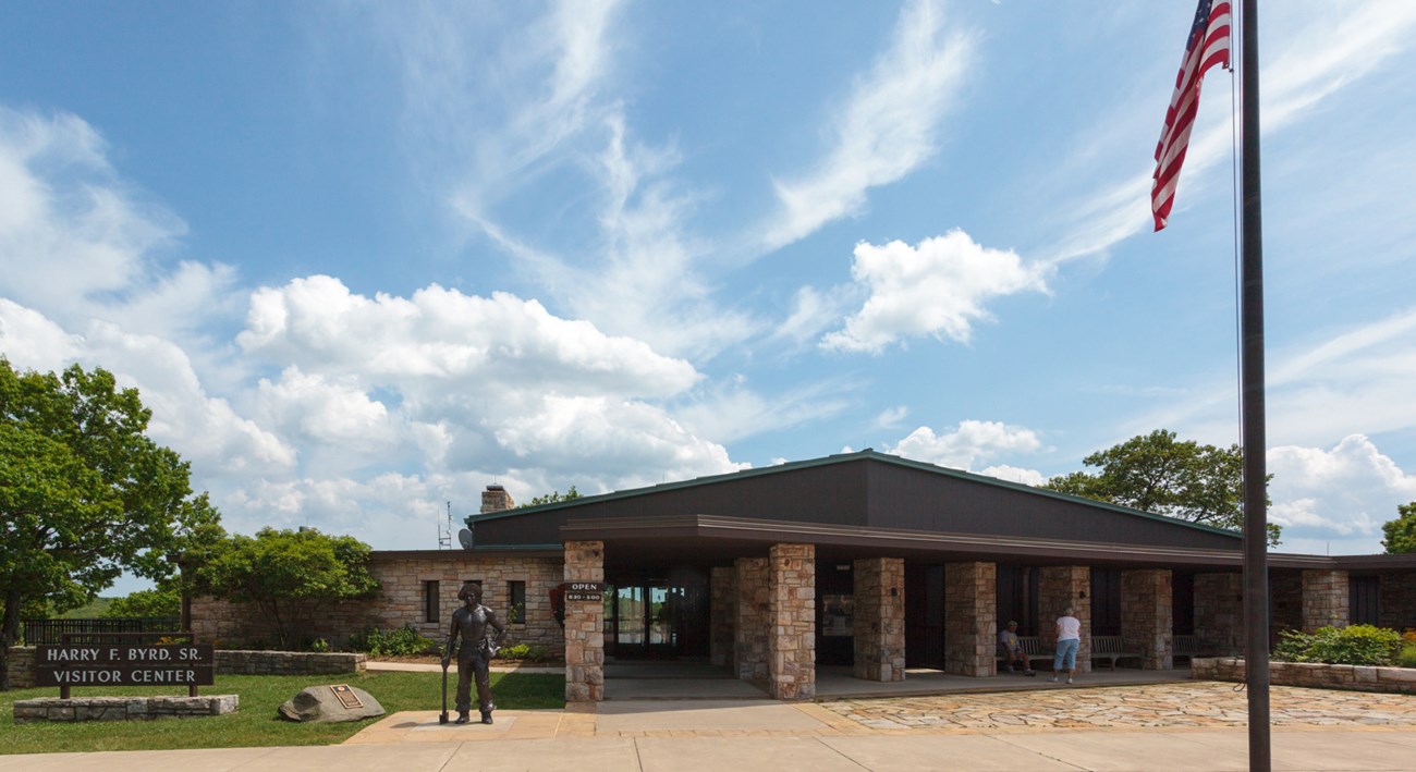 A large stone building sits behind a sign that reads "Byrd Visitor Center"