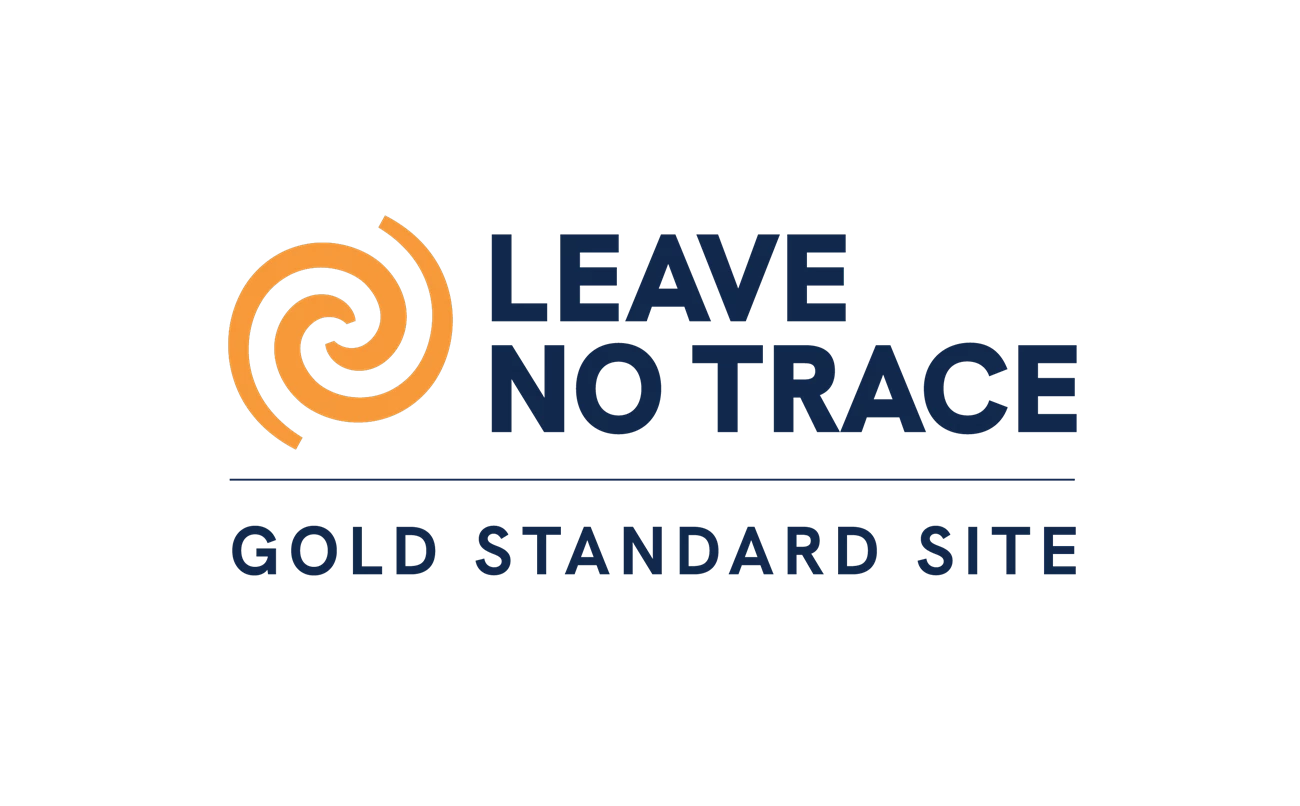 LNTSite GS An orange swirl logo with the words Leave No Trace Gold Standard Site in blue