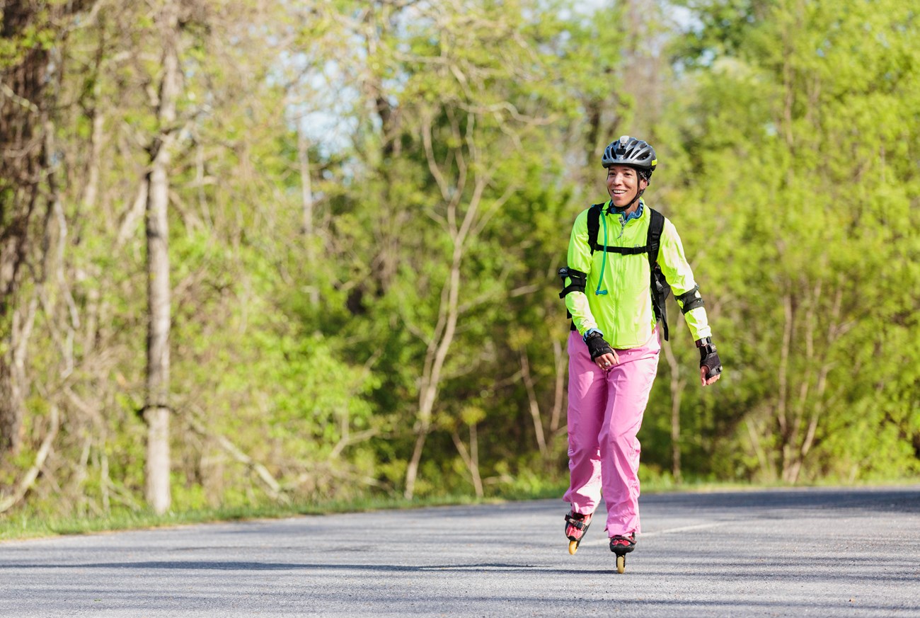 A color photograph of a woman rollerblading on the road.