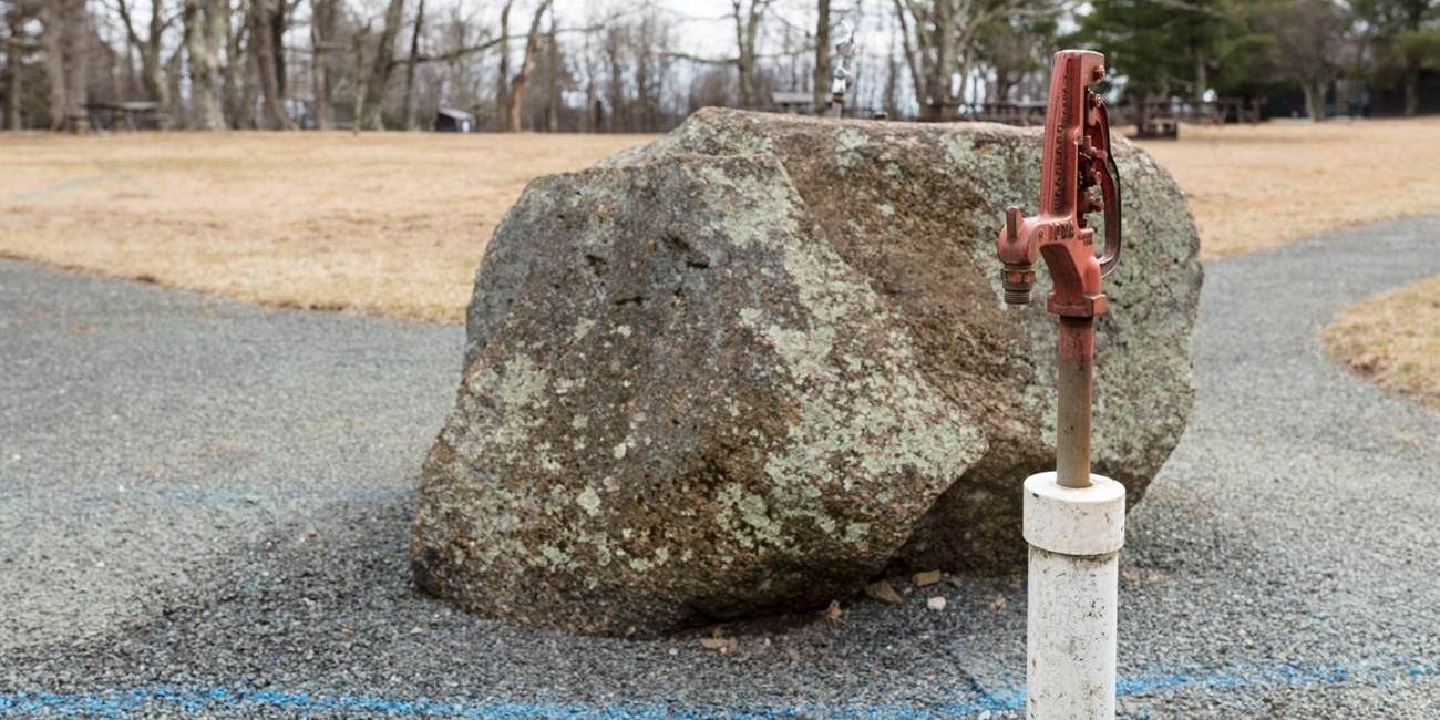 A close up of a water spigot in the middle of a campground.