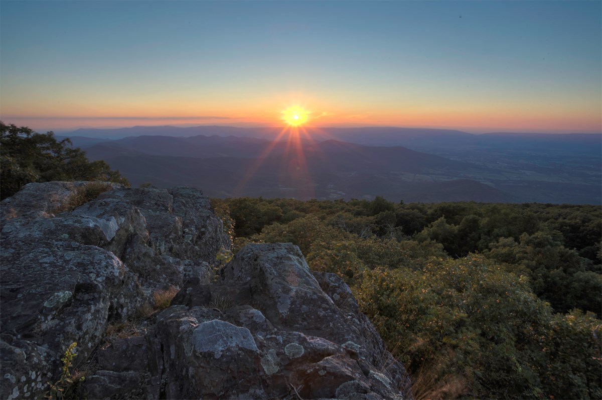 Sunset at Blackrock A sunset at a scenic view with a rock formation and valley in the distance.