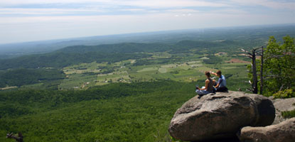 Two visitors catch a wondrous view of the Shenandoah Valley from a rocky ledge in Shenandoah. Two visitors catch a wondrous view of the Shenandoah Valley from a rocky ledge in Shenandoah.