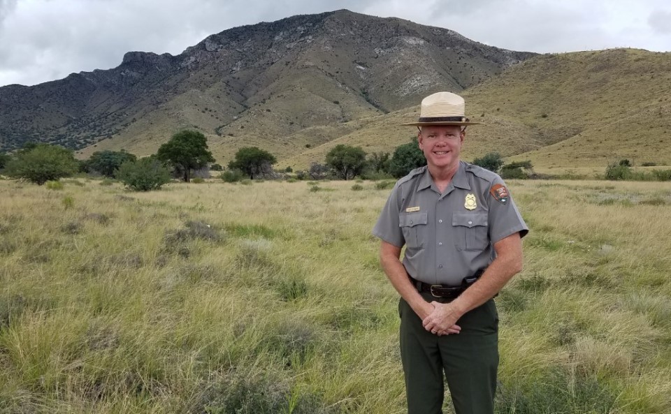 Superintendent Allen Etheridge Male park ranger standing in the Arizona desert with a mountain behind him.