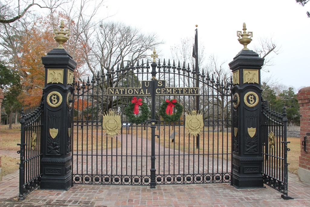 cemetery gate wreath 2 Two wreaths with red ribbons adorn the iron cemetery gates