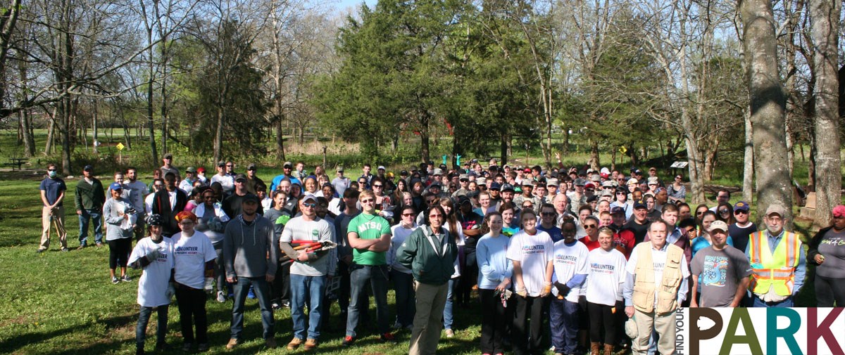 A group of more than 150 volunteers pose in front a stream.