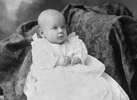 A baby dressed in a fancy, white gown. A baby dressed in a fancy, white gown.