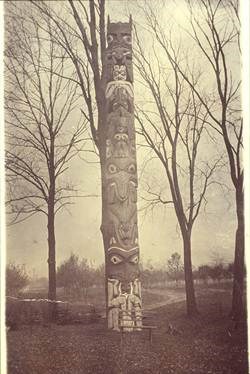 Black and white photograph of the Golden Hill Pole standing outside in front of leafless trees.