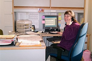 Office with person sitting in a chair at a desk with a computer. Office with person sitting in a chair at a desk with a computer.