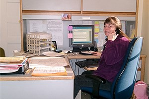 Office with person sitting in a chair at a desk with a computer.