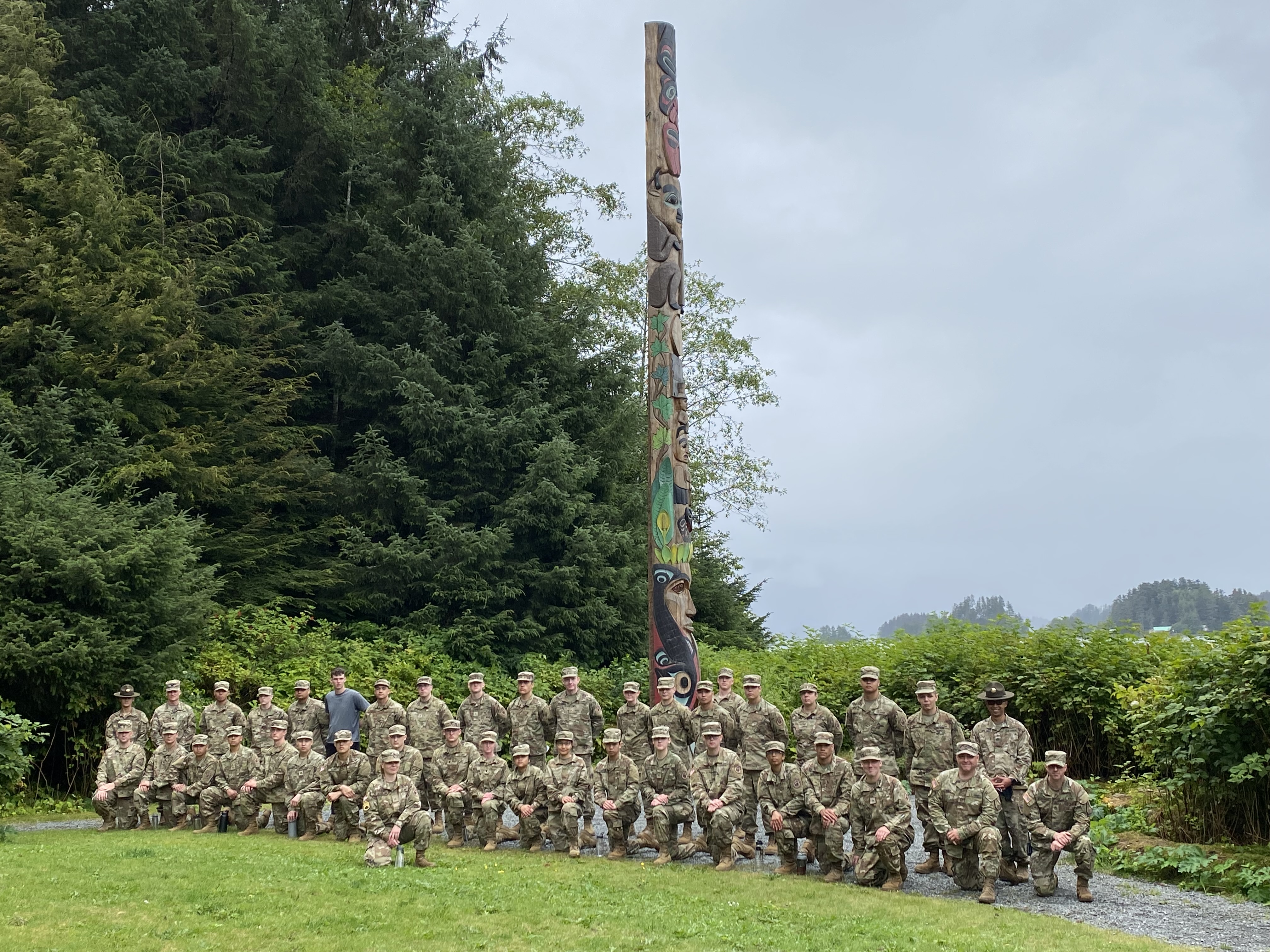 Two rows of soldiers stand in formation in front of a totem pole