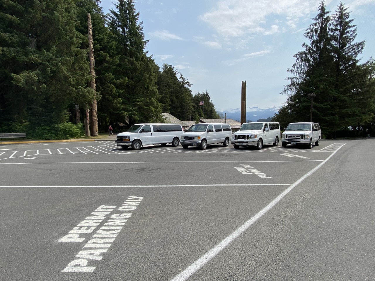 white painted lines stating "permit parking only" and vans parked in the Upper Lot of the Sitka NHP visitor center white painted lines stating "permit parking only" and vans parked in the Upper Lot of the Sitka NHP visitor center