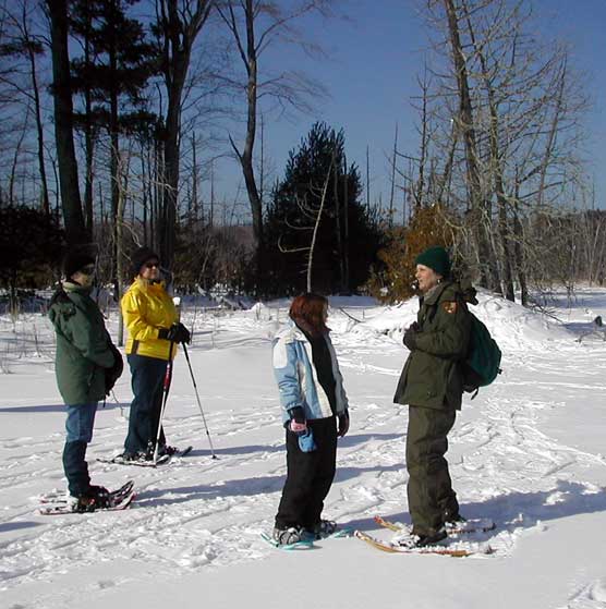 Park Ranger Peg Burman leads visitors on a snowshoe hike to an inland lake.