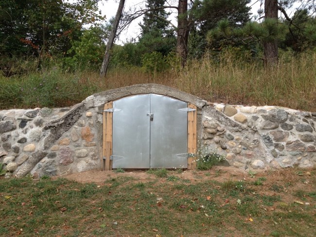 Metal doors on a small arch on a low rock wall