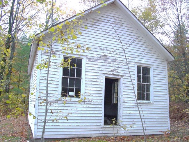 Small white building surrounded by woods