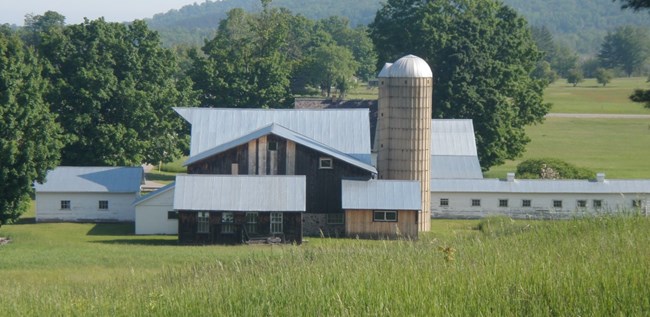 Side view of large barn with silo and outbuildings