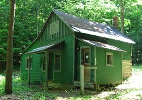 Green cabin with side addition and front porch