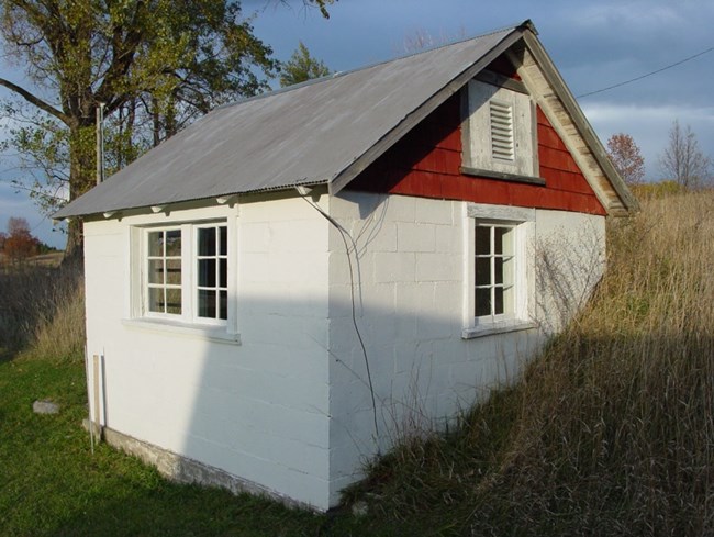 Small white building with red peak built into hillside