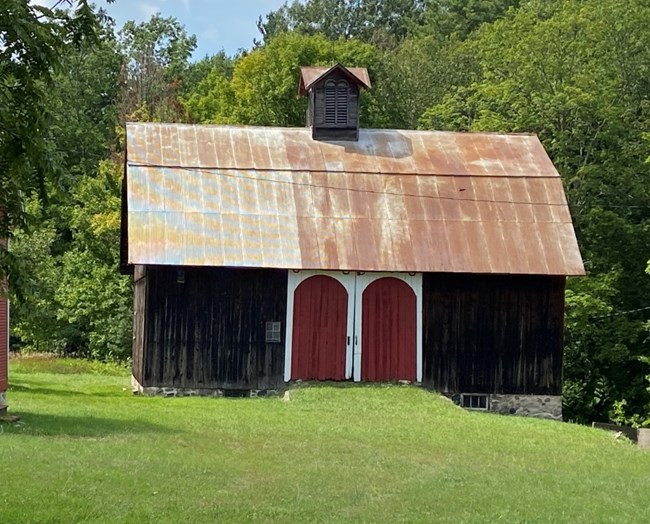 Red barn with white trimmed door and cupola on the roof