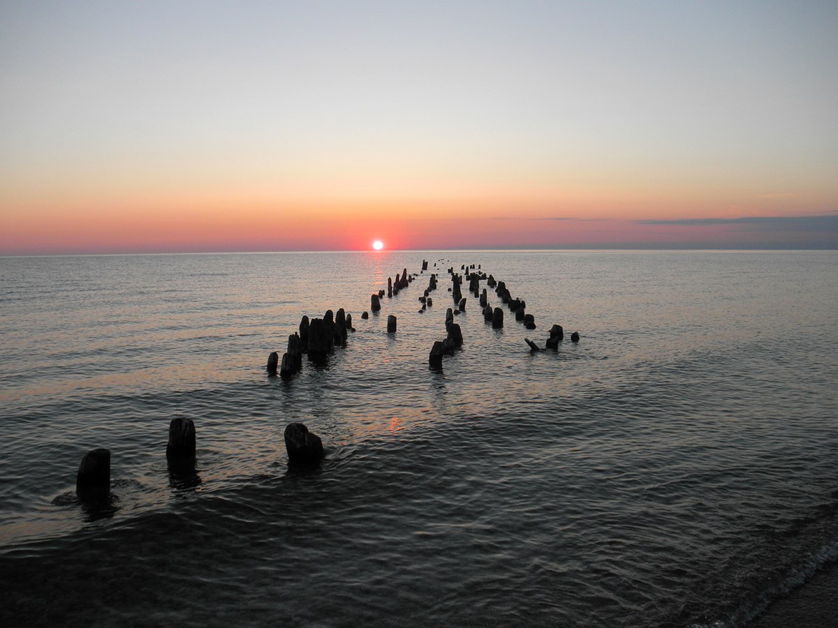 Red suns glows over the lake as it sinks toward the horizon Red suns glows over the lake as it sinks toward the horizon