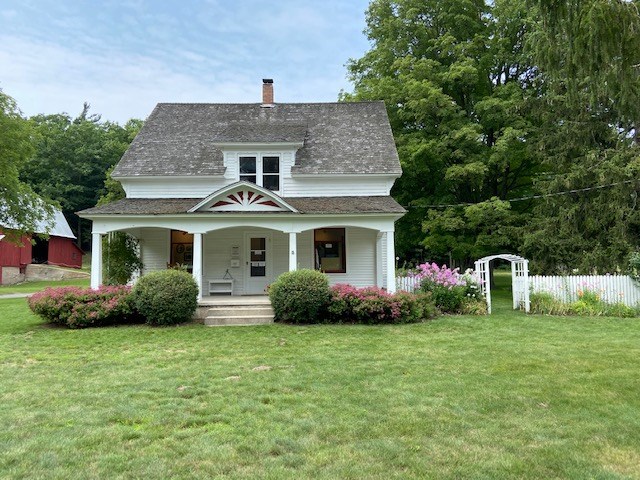 white, two-storied house with porch with decorative gable spanning the front of the house