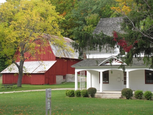 White, gabled house with red barn behind