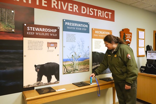 A ranger demonstrates the use of an audio pen to interact with an accessible exhibit.