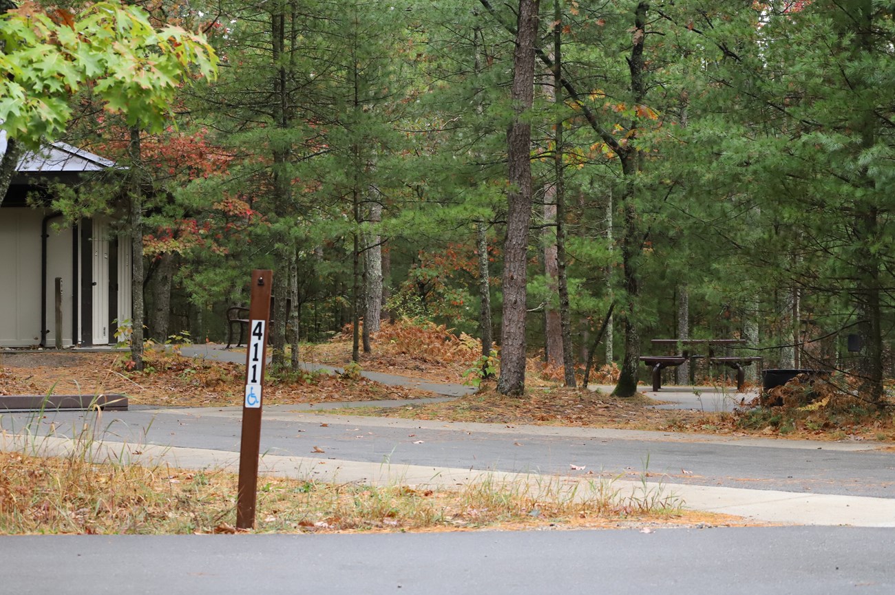 A hard-surfaced campsite with picnic table and paved path to comfort station.