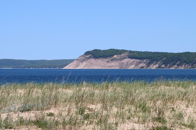 A sand dune on the shores of a large body of water.
