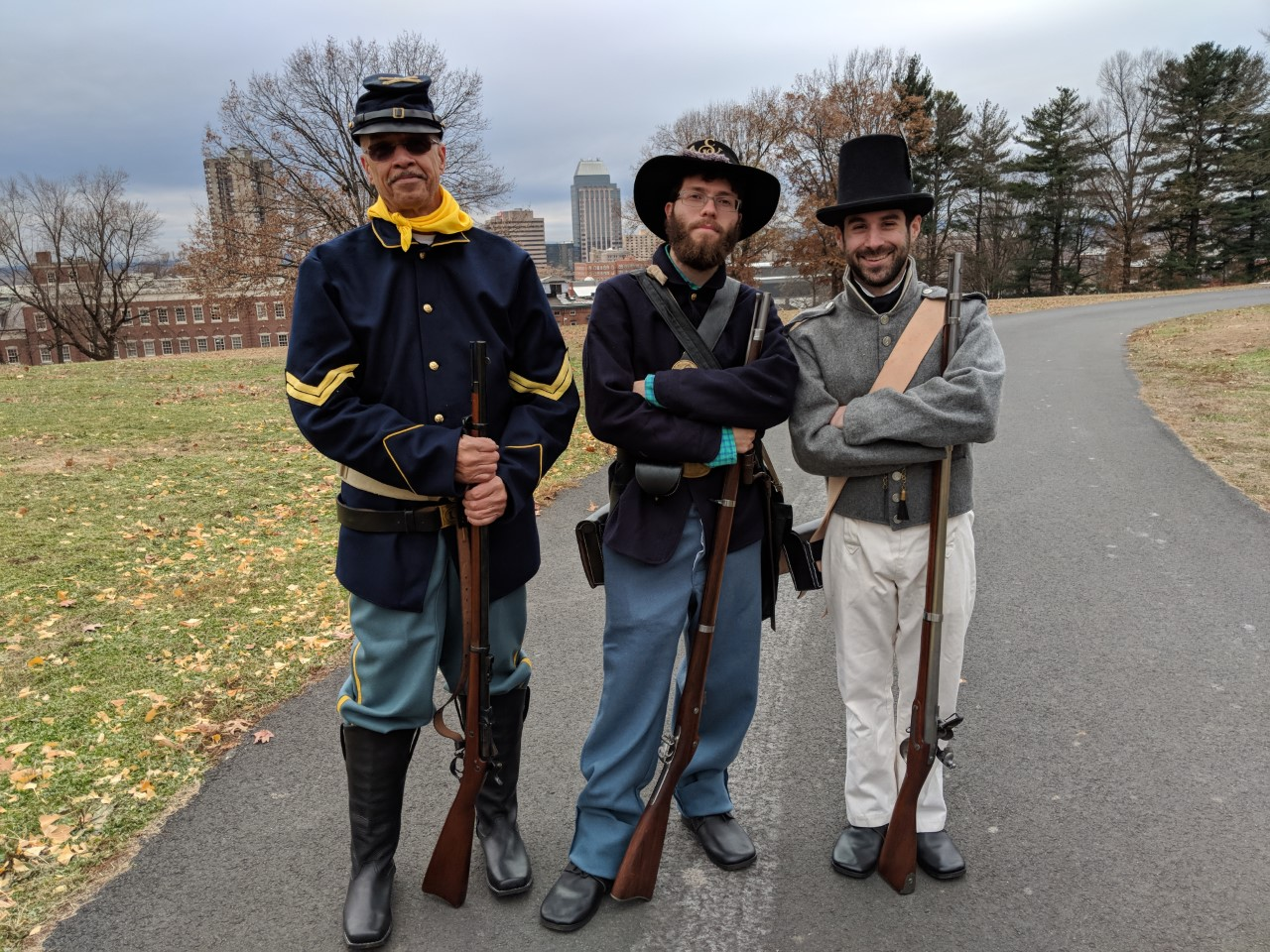 Three men in historic costumes from significant periods of firearms developments