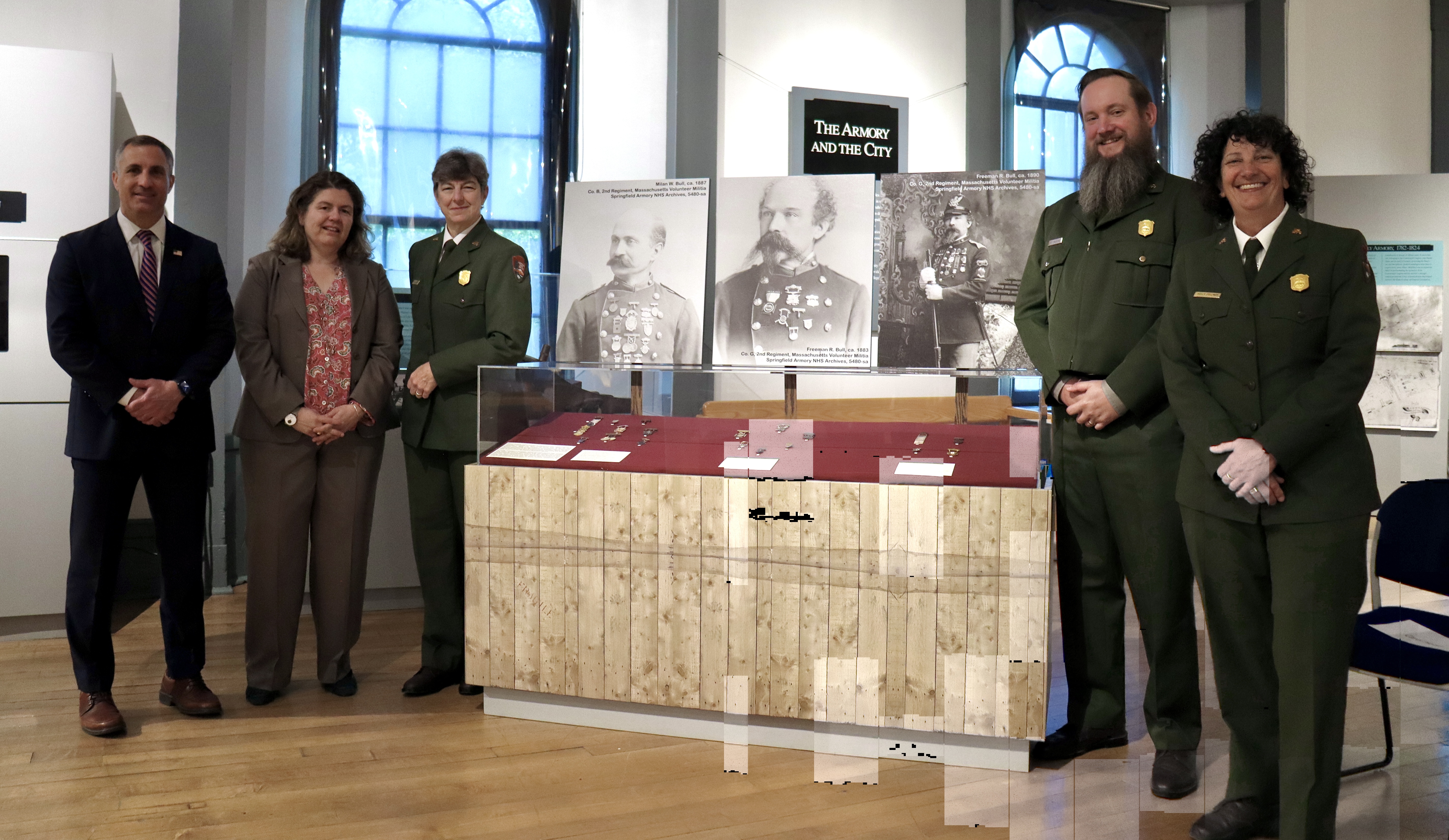 Speakers at the Marksmanship Medal Ceremony A group of five people gathered around a museum display case.