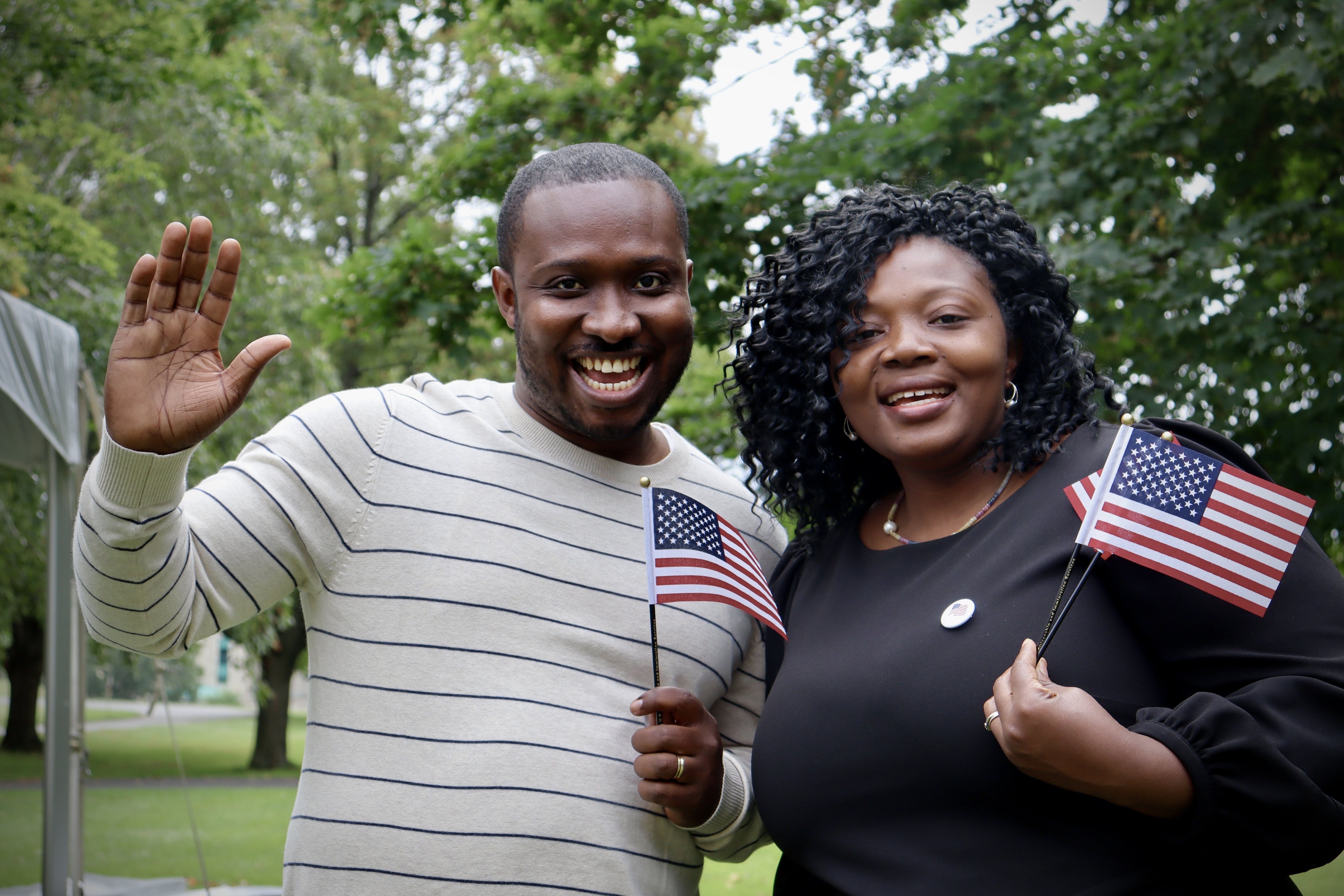 Naturalization-Ceremony-Springfield-Armory Two people smiling and waving holding mini US flags