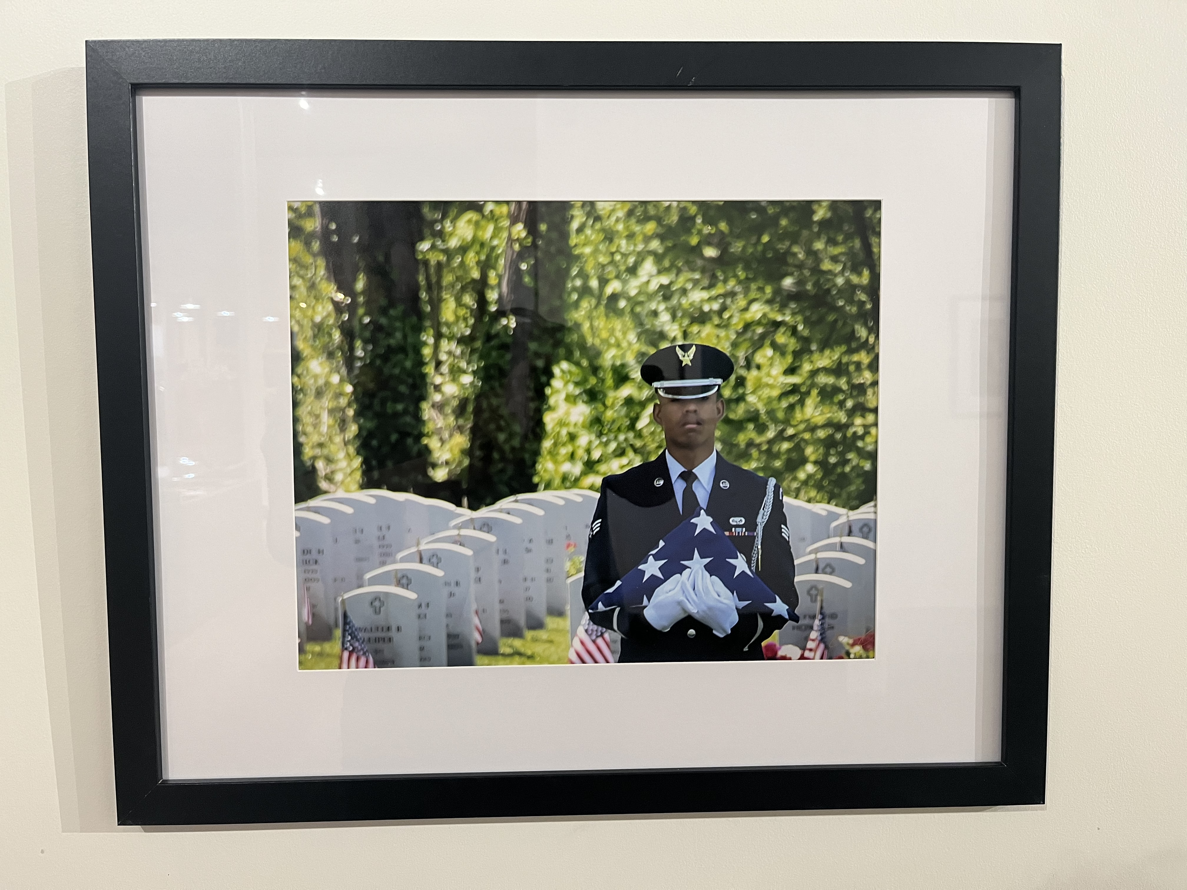 The Paving Stones Soldier holds a folded American flag in a cemetery.