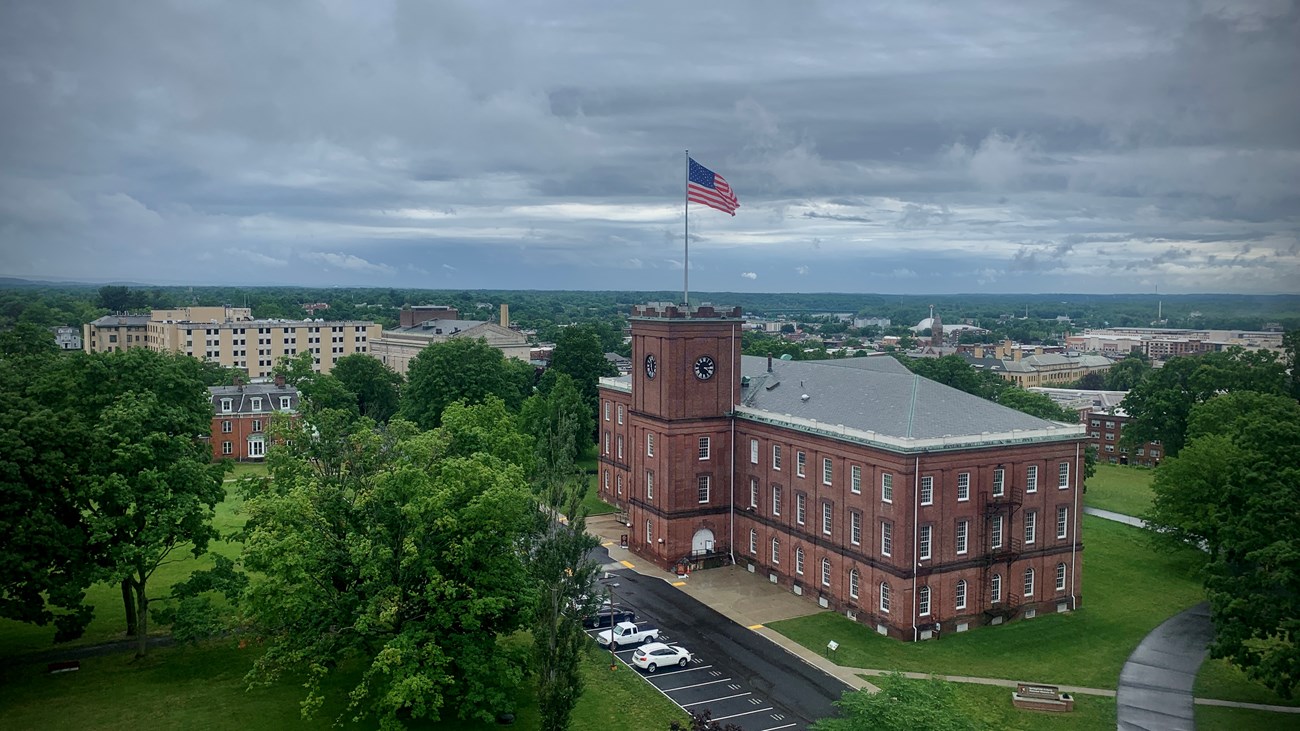 A birdseye view of the Main Arsenal on a cloudy, rainy day. The flag waves in the wind.