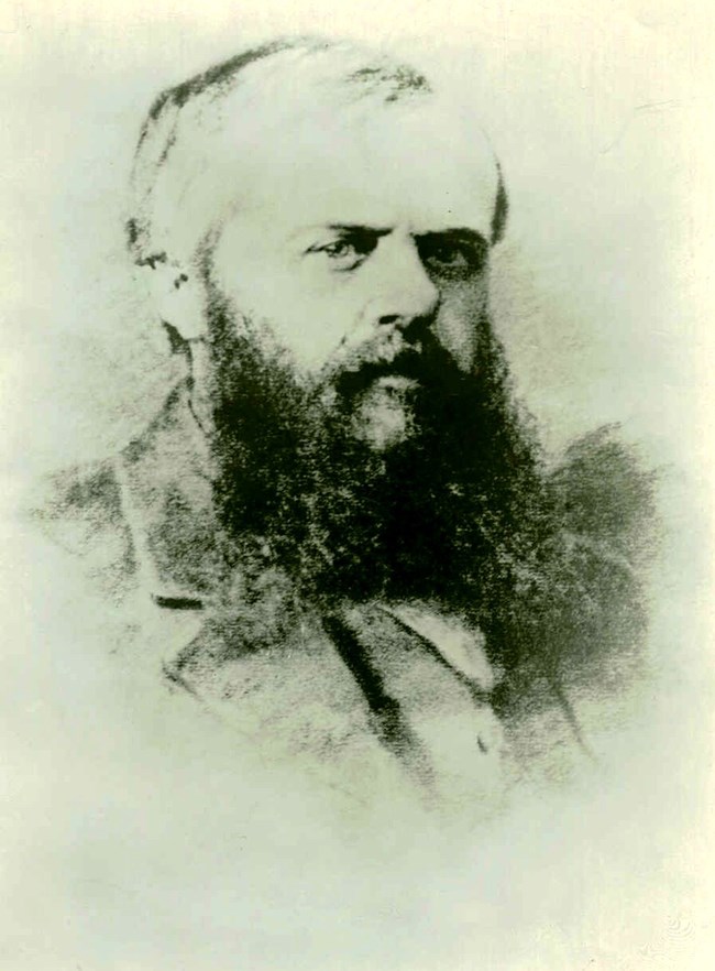 A black and white portrait of a man in civilian clothing. He has a beard.