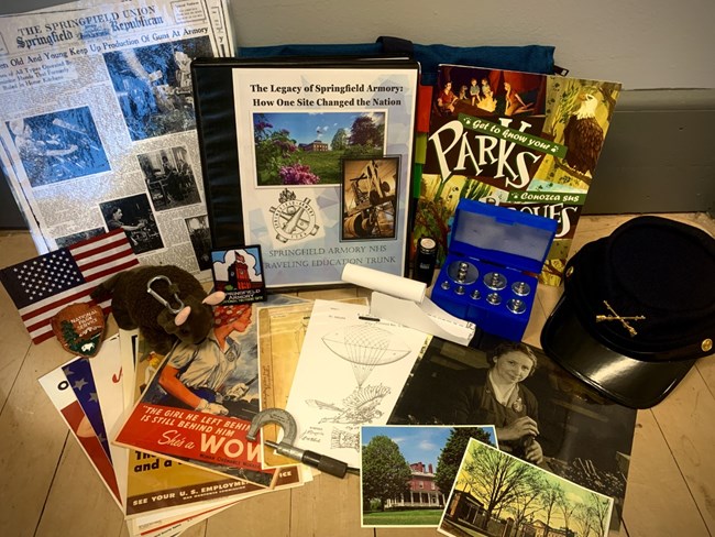 A collection of different materials include a kepi, a binder, photos, an NPS emblem patch, a stuffed animal bison, the American Flag and more.