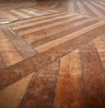 Parquet flooring; the design is strips of wood creating squares.