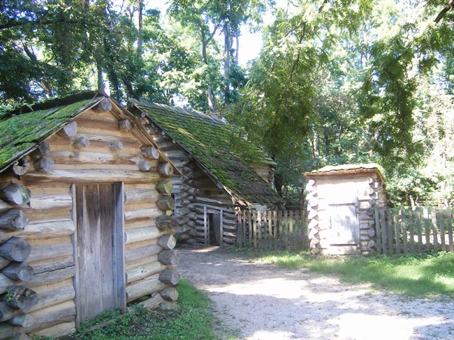 Several small log cabins in a reconstructed, early 1800s village.