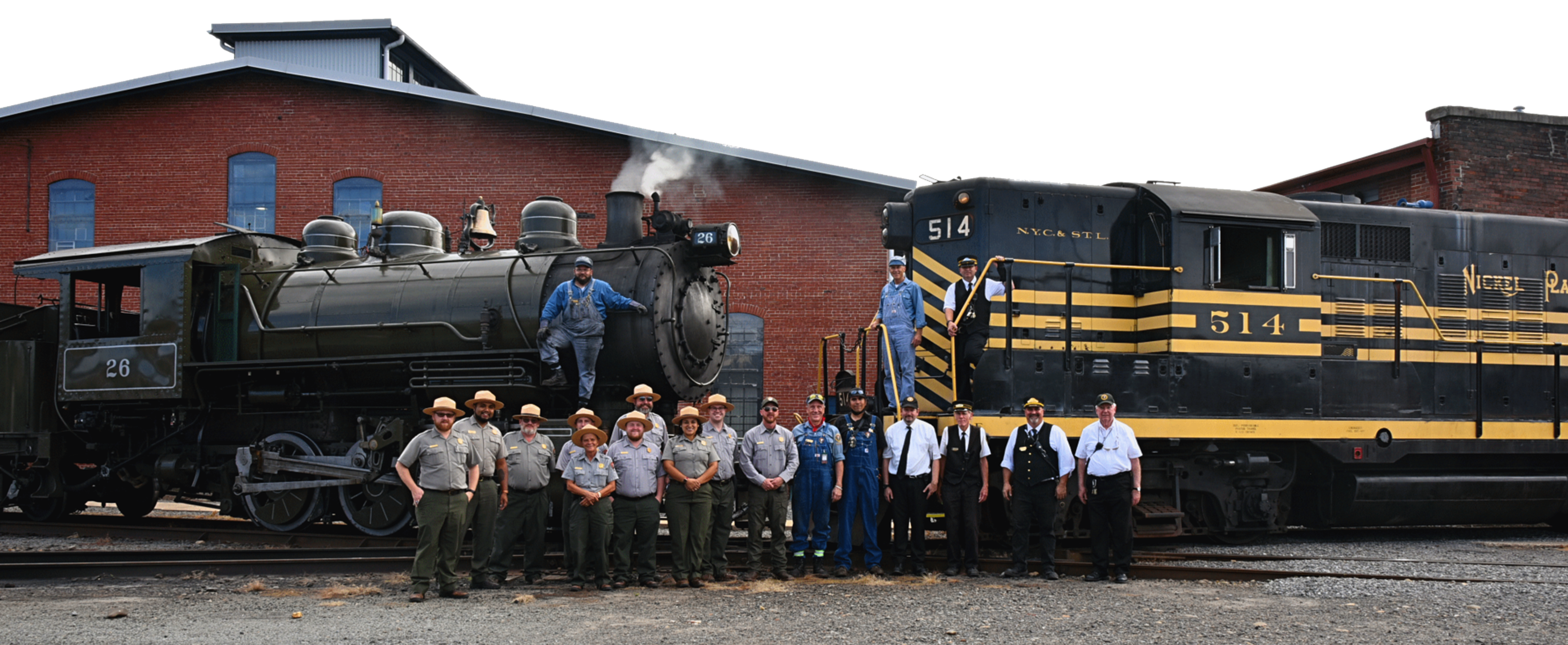 Group photo in front of a steam locomotive and diesel locomotive.