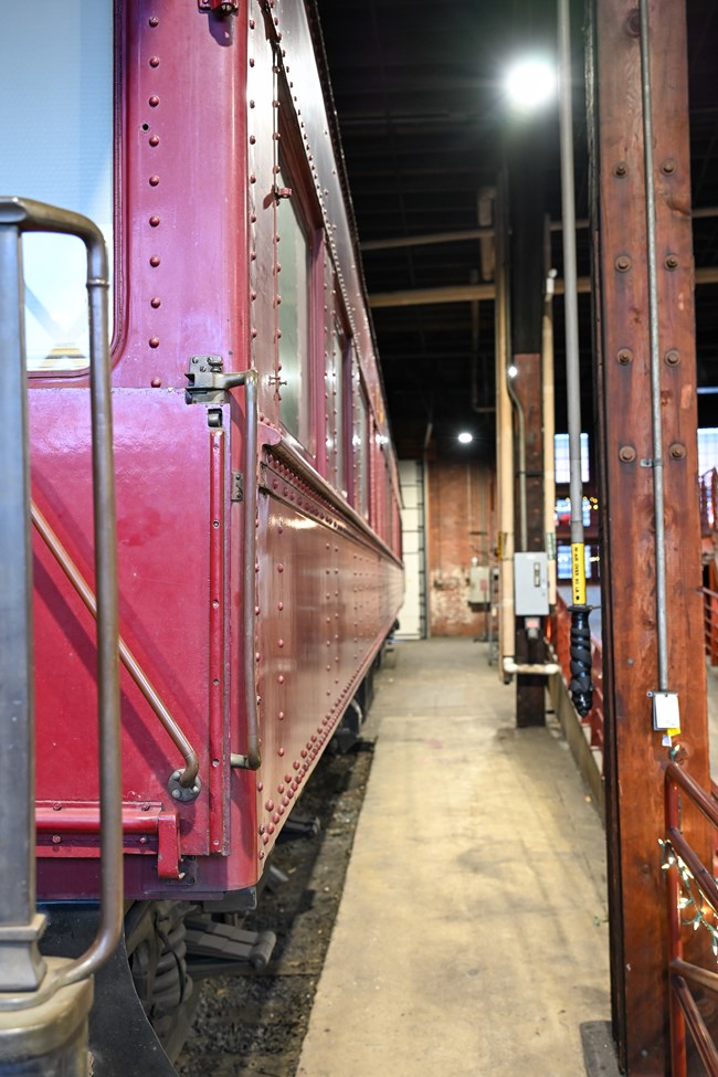 Pathway from locomotive shop to roundhouse, with a train car being worked on to the left.