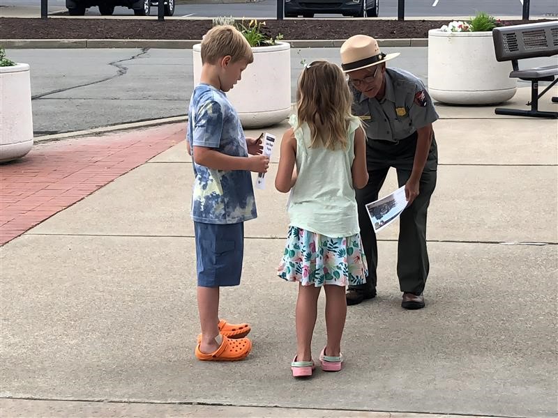 A ranger bends over to provide badges to youth