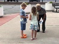 A ranger bends over to provide badges to youth